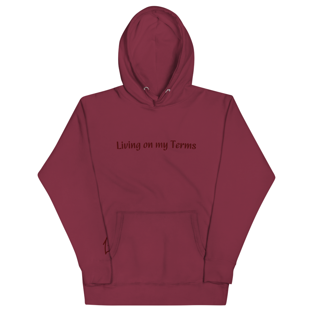"Red hoodie with Red embroidered text that reads 'Living on my Terms'. The hoodie features a comfortable fit and a bold font. The design conveys a spiritual identity and sense of individuality, making it a great choice for anyone who is not afraid to stand up for what they believe in."
